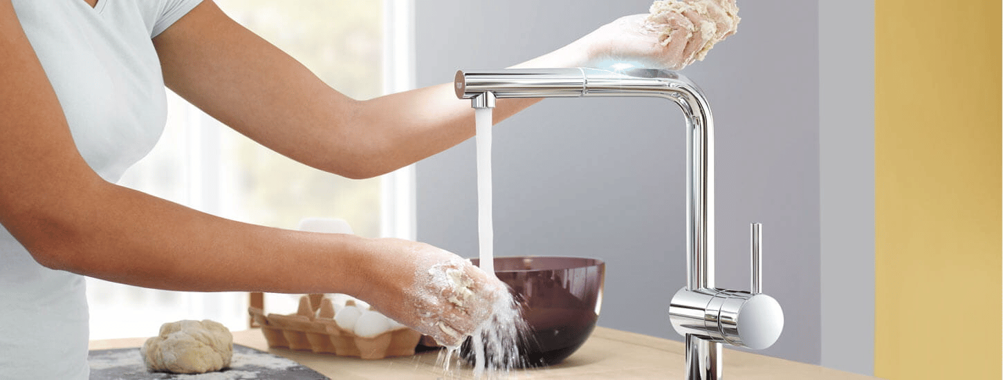 A person washing her hands through a touchless faucet