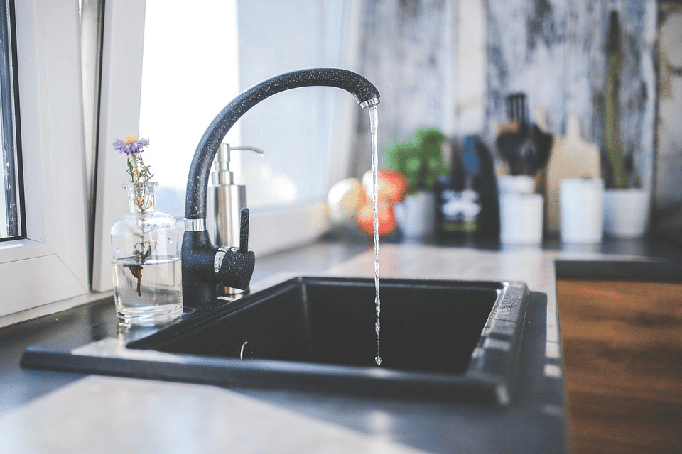 Black kitchen faucet dripping water on the sink
